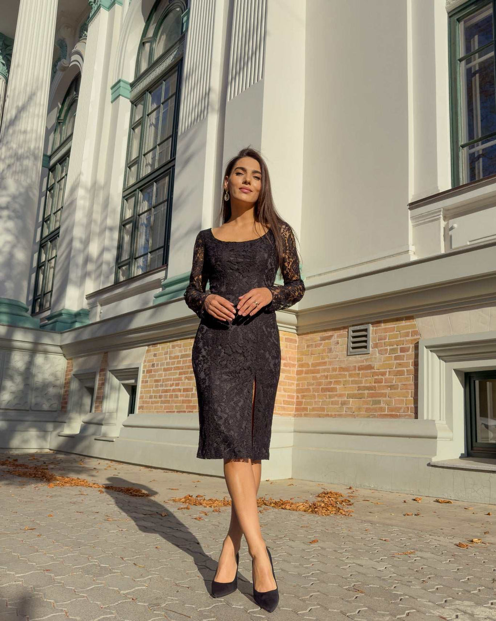Rochie neagra din dantelă cu mâneci lungi și slit lateral în partea stângă.