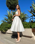 Rochie cununie civila midi albă cu slit și decolteu într-un cadru urban, material satin, croială A-line, fără mâneci.