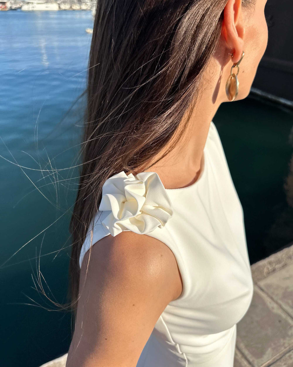 Rochie alba petrecere fără mâneci cu accesoriu floral și slit elegant, vedere laterală.