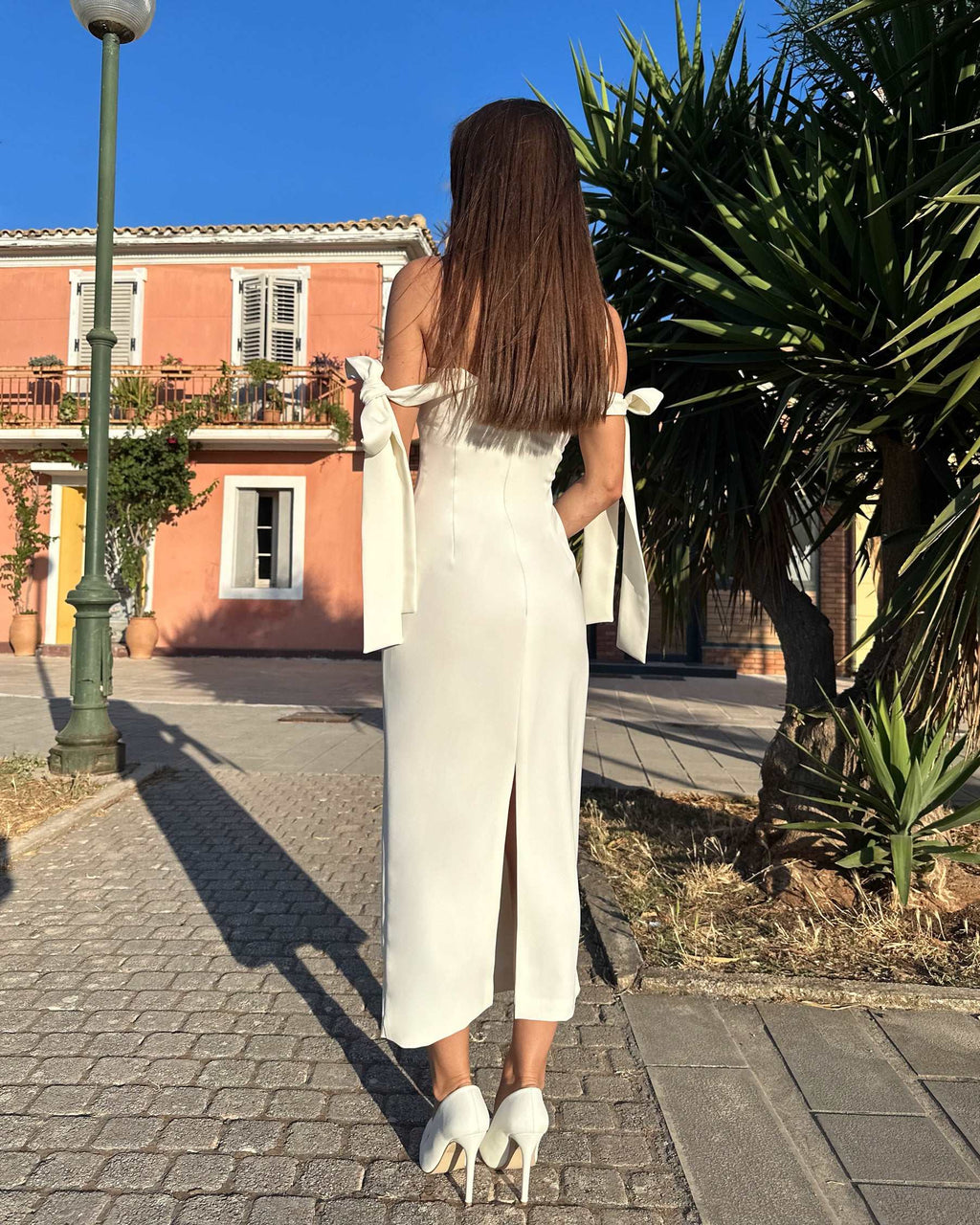 Rochie alba elegantă cu slit lateral și bretele evazate, design sofisticat ideal pentru ocazii speciale.