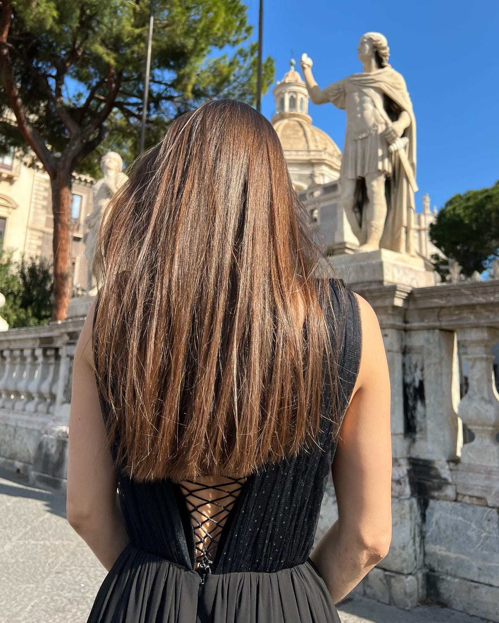 Rochie nunta neagră cu corset din dantelă și șiret reglabil, fundal arhitectural.